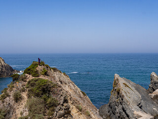 Fototapeta na wymiar Man on top of cliff in beach during summer, in costa vicentina, alentejo, portugal 