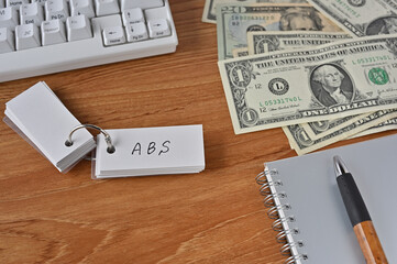 On the desk were bills, a notebook, and a word book with the word ABS written on it. It was an abbreviation for the financial term Asset Backed Security.