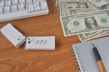 On the desk were bills, a notebook, and a sticky note with the word APS written on it. It was an abbreviation for the financial term average propensity to save.