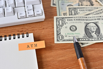 On the desk were bills, a notebook, and a sticky note with the word ATM written on it. It was an...