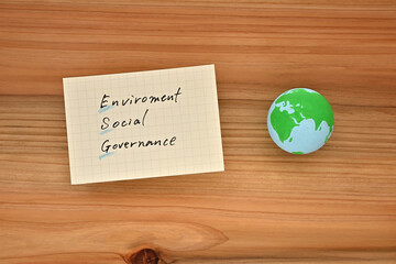 There is an earth ball and a piece of paper with Environment Social Governance written on it on a cedar board.