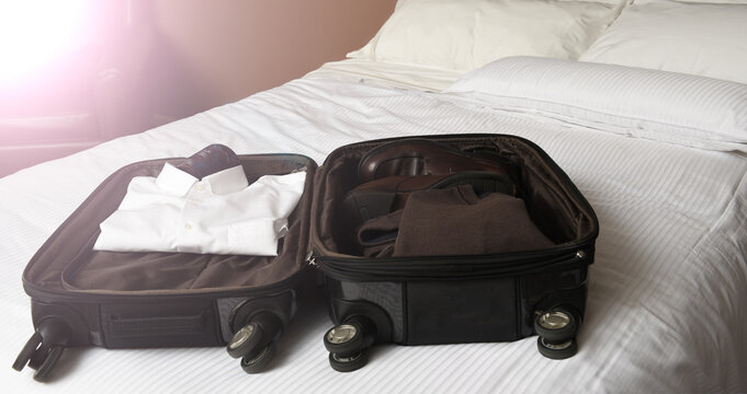 A businessman's open suitcase on top pof a hotel bed with intentional flare from a window.