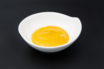 Yellow Souce in white dish on black, dark background