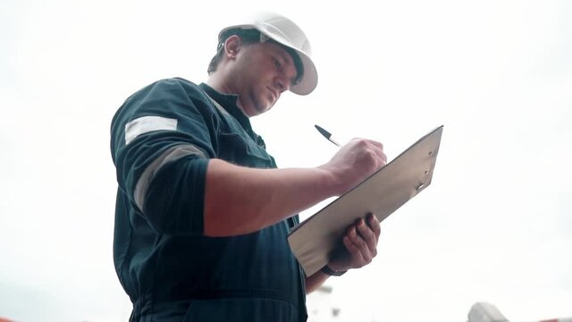 Marine Deck Officer or Chief mate on deck of offshore vessel or ship walking on deck, doing inspection with checklist