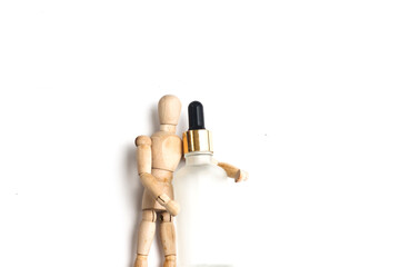 Wooden mannequin holding a bottle over white background.
