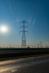 High Energy pole near road between fields with shining sun at sunny morning