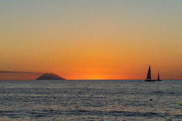 Beautiful sunset over Tyrrhenian Sea and Stromboli island with a sailboat viewed from Tropea,...