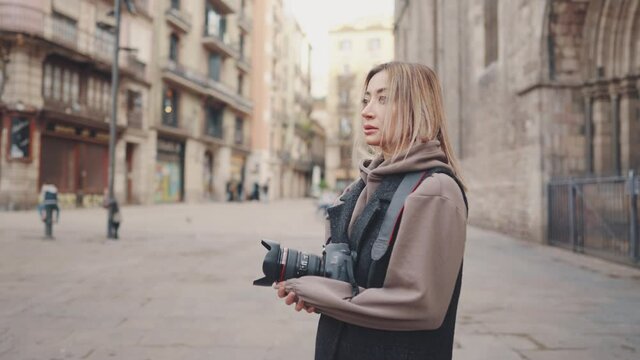Beautiful Female tourist with dslr photo camera walking through old town streets, Barcelona, Spain. She takes photos