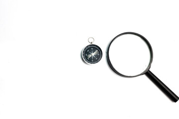 White table as background with compasses and magnifying glass on top.