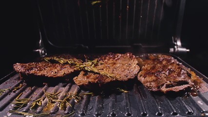 Delicious juicy meat steak cooking on grill. Aged prime rare roast grilling tenderloin fresh marble tenderness beef. Prime beef fry on electric roaster, rosemary, black pepper, salt. Slow motion.