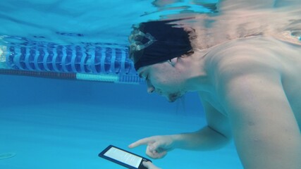 Man reads an electronic book underwater. This is a special waterproof electronic device. You can...