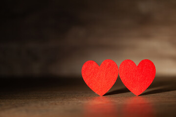 Fototapeta premium Against the background of a dark tree two red hearts, use as a background or postcard