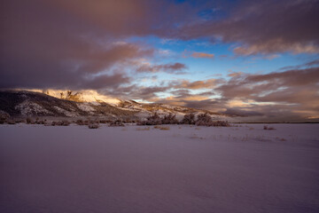 Image of a snowy sagebrush, desert and cloudy landscape.