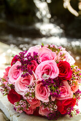 Pink and purple rose bouquet with wedding rings inside the flower and water behind
