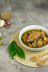 Semur Ayam Tahu, Indonesian traditional food made with chicken, tofu, spices, soy sauce and palm sugar. Grey grainy background, copy space for text. 