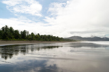 Paisaje del agua del mar reflejando los arboles, el cielo y las montañas