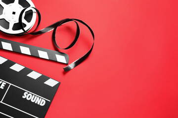 Clapboard and reel on red background, flat lay with space for text. Video production equipment
