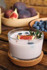 Delicious fig smoothie in glass on wooden table