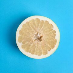 Fresh cut pomelo fruit on blue background, top view
