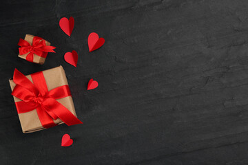 Gift boxes and paper hearts on black background, flat lay with space for text. Valentine's Day...
