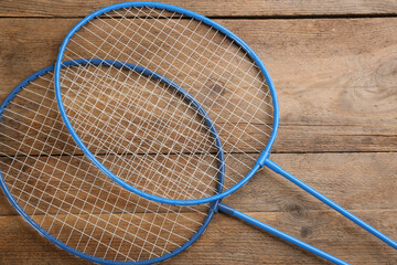 Rackets on wooden table, flat lay. Badminton equipment