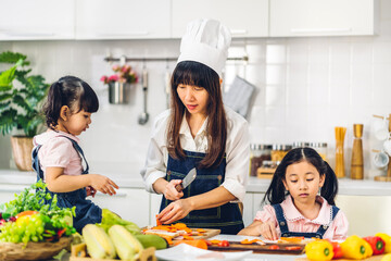Portrait of enjoy happy love asian family mother and little asian girl daughter child having fun cooking together with fresh vegetable salad and sandwich ingredients on table in kitchen