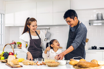 Obraz na płótnie Canvas Portrait of enjoy happy love asian family father and mother with little asian girl daughter child having fun cooking together with baking cookies and cake ingredients on table in kitchen