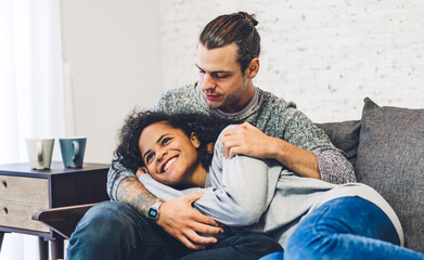Romantic young happy love couple caucasian man and african american woman smile and have fun hugging together in valentine day on the bed at home