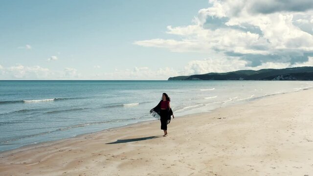 Aerial view on girl dancing on a sand beach.
