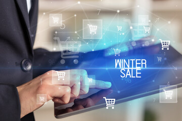 Young person makes a purchase through online shopping application with WINTER SALE inscription