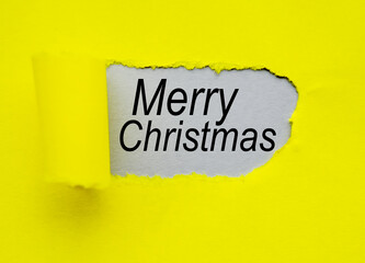 Merry Christmas written on a hole on a yellow paper background