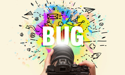 Close-up of a hand holding digital camera with abstract drawing and BUG inscription