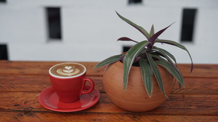 coffee on a brown wooden table with a flower pot