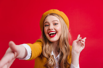 Cheerful french female model smiling at camera. Studio shot of emotional girl in yellow beret.