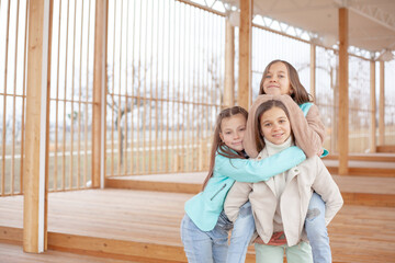 Group of funny kids friends hugging, smiling at the wooden background on the park