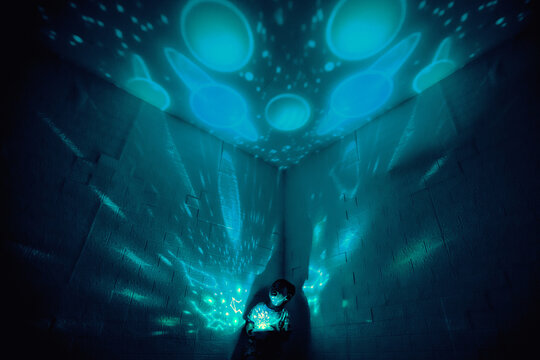 Little boyl in his room with night light projecting stars on room ceiling. Children read before bedtime.