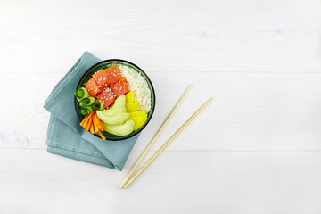Poke bowl with salmon, rice, avocado, cucumber, mango, pepper, carrot. Hawaiian diet food with fish .Top view. Flat lay.