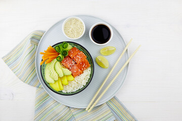 Poke bowl with salmon, rice, avocado, cucumber, mango, pepper and carrot. Hawaiian diet food with fish .Top view. Flat lay.