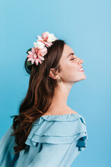 Naklejka premium Beautiful girl sincerely smiling on isolated background. Model in crown of flowers posing for portrait in profile