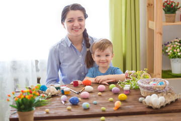 Charming mother and son celebrating Easter. Family celebrating Easter. Parent and kid play indoors. Decorated home and spring flowers