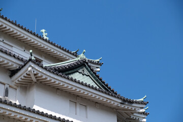 Fototapeta na wymiar Wakayama, Wakayama Prefecture / Japan, October 15 2020: Close-up low angle view of Wakayama Castle tiled roof and a clear blue sky.