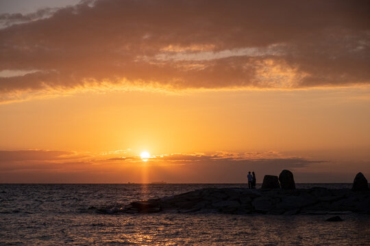 Cloudy sunset with silhouette of couple standing on a rocky shore at Shirahama Beach in Wakayama Prefecture, Japan © Tobias Schwindling