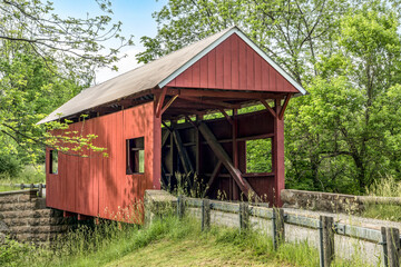 The historic red Erskine Covered Bridge crosses Middle Wheeling Creek in rural wooded Washington County, Pennsylvania.