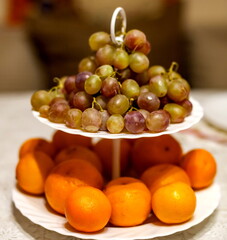 Grapes and tangerines on a two-tier white plate closeup