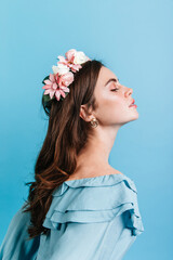 Profile shot of aristocratic girl in blouse with frill. Lady with flowers in her hair posing...