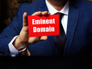 Business concept meaning Eminent Domain with sign on blank card in hand.