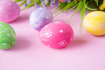 Obraz na płótnie Canvas Easter eggs with wild flowers on a wooden pink table background