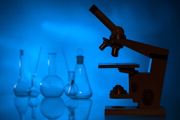 Microscope as a symbol of laboratory research. Iledovinia in chemical laboratory. Medical flasks in background. Concept of working with a microscope. Exploring something with a microscope.