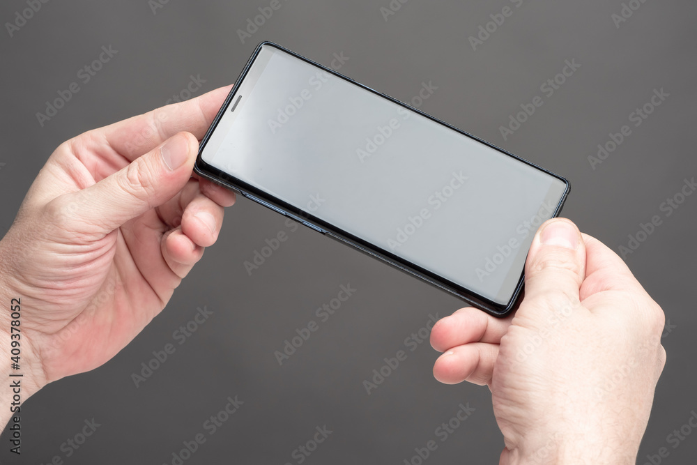 Poster touch screen phone in human hands. smartphone on a dark background. close-up of a smartphone with sc
