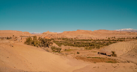 Fototapeta na wymiar Panorama view of desert and clay houses and the Kasbah (fortress) in the ancient town of Aid Benhaddou, Morocco with Atlas mountains in the background